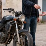 Un homme donne la clé d'une moto lors d'une vente.