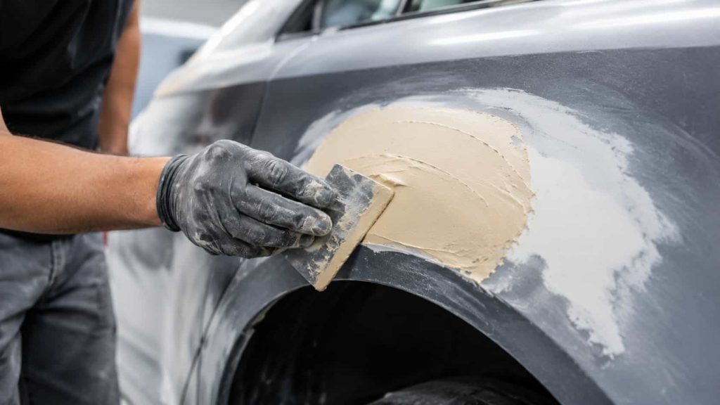 Application d'un mastic pour carrosserie.
