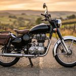 Moto de style vintage stationnée sur une route de campagne au coucher du soleil.